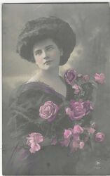 GLAMOROUS YOUNG WOMAN WITH FLOWERS  (REAL PHOTOGRAPHIC COLOURED POSTCARD) c1910